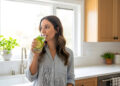 Woman Drinking Refreshing Infused Water in Bright White Kitchen