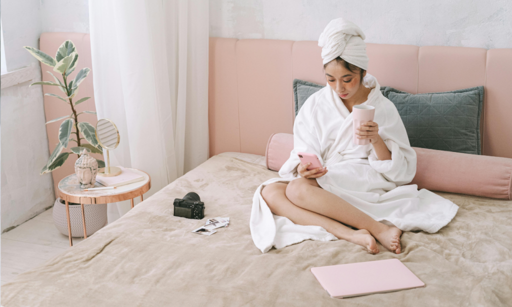 woman in her bed drinking coffee and writing in her journal as her morning routine