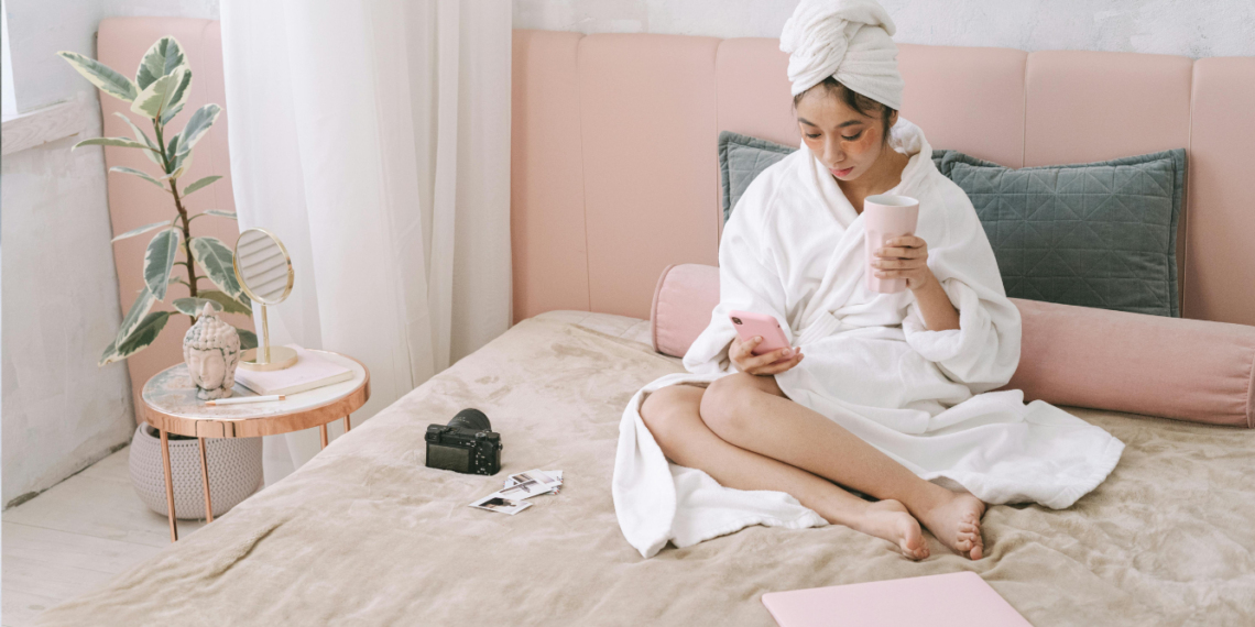 woman in her bed drinking coffee and writing in her journal as her morning routine