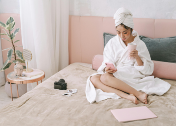 woman in her bed drinking coffee and writing in her journal as her morning routine