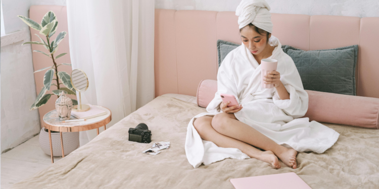 woman in her bed drinking coffee and writing in her journal as her morning routine